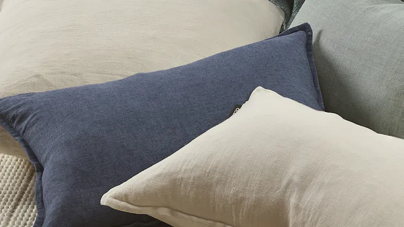 Close-up of a deep blue cushion paired with cream and green cushions, showing soft fabric texture Close-up of a deep blue cushion paired with cream and green cushions, showing soft fabric texture