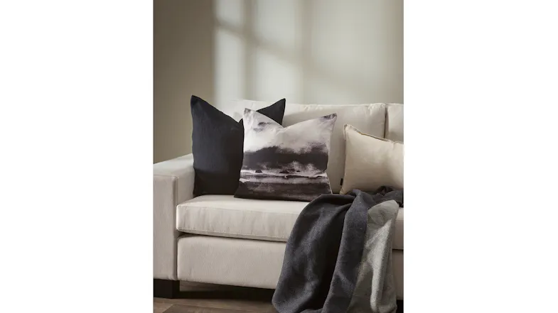 Angled view of a sofa with monochrome cushions and a grey throw Angled view of a sofa with monochrome cushions and a grey throw