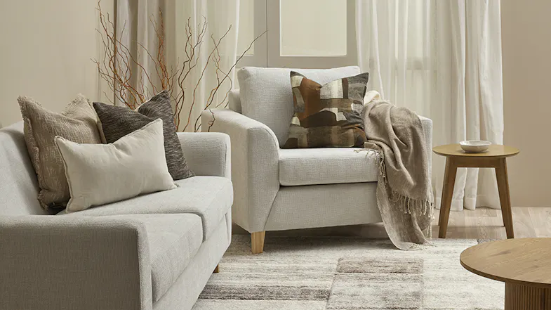 A view of a brightly lit living room with cushion displayed on an armchair A view of a brightly lit living room with cushion displayed on an armchair