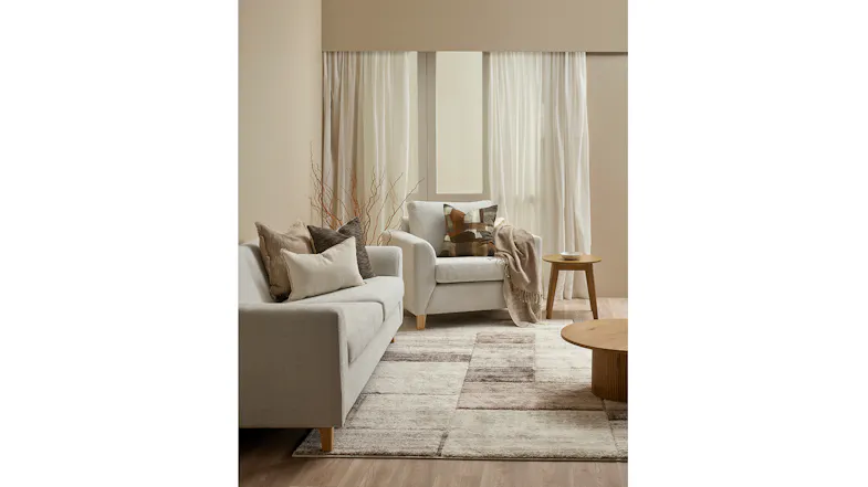 A full view of a brightly lit living room with cushion displayed on an armchair A full view of a brightly lit living room with cushion displayed on an armchair