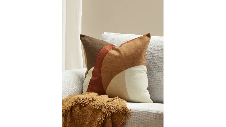 Light-coloured sofa with an Ellis cushion in desert tones, paired with a fringed mustard throw Light-coloured sofa with an Ellis cushion in desert tones, paired with a fringed mustard throw