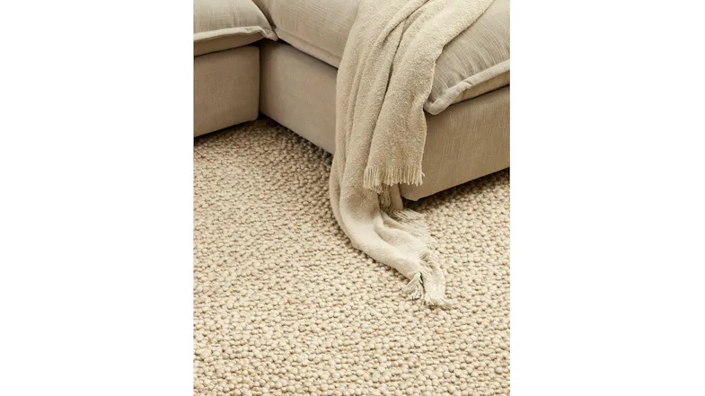 Close-up of a textured ivory Lily Throw draped onto a matching pebble-style area rug Close-up of a textured ivory Lily Throw draped onto a matching pebble-style area rug
