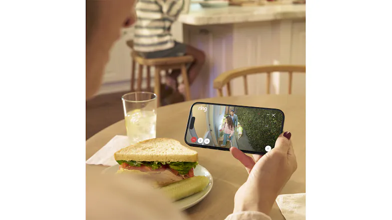 Person eating a sandwich while watching a live 2K Ring camera feed of their porch on a smartphone Person eating a sandwich while watching a live 2K Ring camera feed of their porch on a smartphone