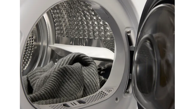 A close-up view of the dryer's interior with a grey sweater inside A close-up view of the dryer's interior with a grey sweater inside