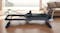 The PROTRAIN Reformer Pilates device set up in a bright, modern home living room The PROTRAIN Reformer Pilates device set up in a bright, modern home living room