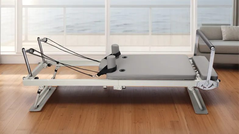 The PROTRAIN Reformer Pilates device set up in a bright, modern home living room The PROTRAIN Reformer Pilates device set up in a bright, modern home living room