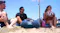A couple of friends hanging at the beach with the speaker positioned at the centre A couple of friends hanging at the beach with the speaker positioned at the centre