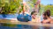 A bunch of people splashing in the pool with the speaker sitting on the side A bunch of people splashing in the pool with the speaker sitting on the side