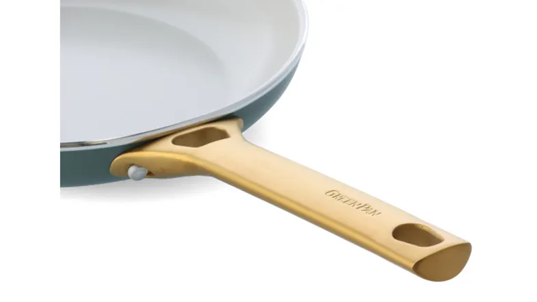 Detail shot of the sturdy gold handle attachment on a blue ceramic GreenPan frying pan Detail shot of the sturdy gold handle attachment on a blue ceramic GreenPan frying pan