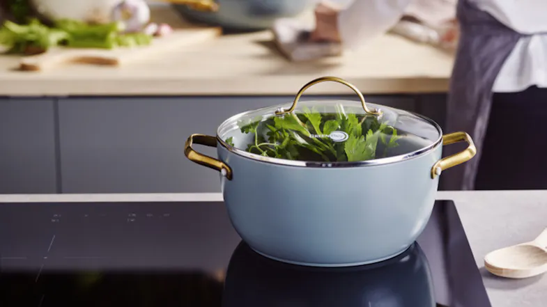 GreenPan Padova pot sitting on a black induction cooktop filled with green herbs GreenPan Padova pot sitting on a black induction cooktop filled with green herbs
