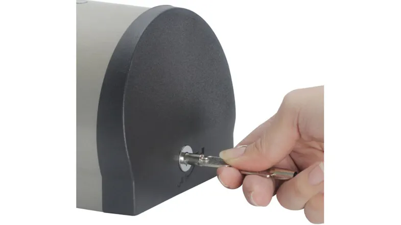 A hand inserting a key in a soap dispenser A hand inserting a key in a soap dispenser