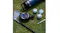 Black JLab Pop Party speaker on grass with golf clubs, balls, and a water bottle Black JLab Pop Party speaker on grass with golf clubs, balls, and a water bottle