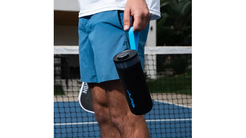 A man stands on a court holding the JLab Go Party Bluetooth speaker by its blue carrying loop A man stands on a court holding the JLab Go Party Bluetooth speaker by its blue carrying loop