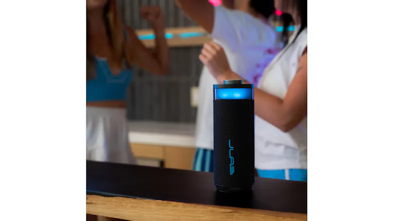 JLab speaker with blue lights on a counter at a party with people blurred in the background JLab speaker with blue lights on a counter at a party with people blurred in the background