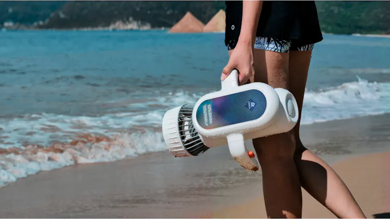 A person carries an underwater scooter with orange triggers by the sea A person carries an underwater scooter with orange triggers by the sea