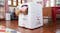 A cat stepping out of a white Hello Kitty–themed automatic litter box A cat stepping out of a white Hello Kitty–themed automatic litter box