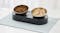 PetKit dual feeding station with two stainless steel bowls filled with kibble and diced food on a light mat PetKit dual feeding station with two stainless steel bowls filled with kibble and diced food on a light mat