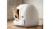 A cat stepping out of a white, dome‑shaped automatic litter box in a room A cat stepping out of a white, dome‑shaped automatic litter box in a room