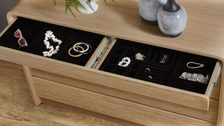 Top drawer of the Arc Lowboy open, showing a black felt-lined jewelry organiser with rings and gems Top drawer of the Arc Lowboy open, showing a black felt-lined jewelry organiser with rings and gems