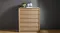 Front view of the Arc 6 Drawer Tallboy in light wood against a dark grey wall Front view of the Arc 6 Drawer Tallboy in light wood against a dark grey wall