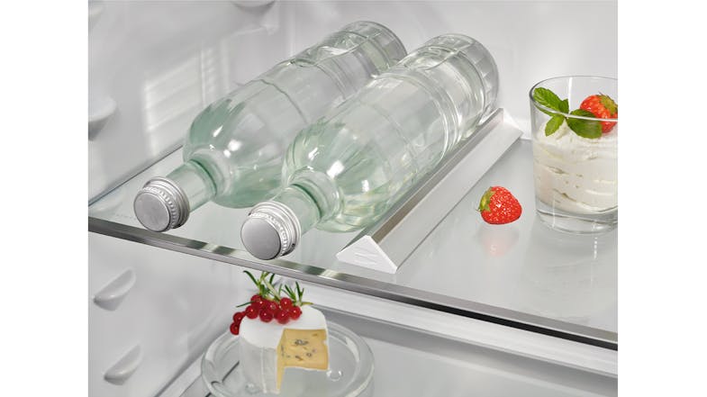 Two glass bottles resting on a glass shelf above a cake Two glass bottles resting on a glass shelf above a cake