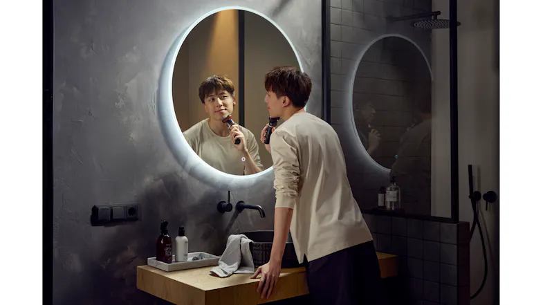 A view of a man in a bathroom grooming his face using the Philips 5000x Series Shaver A view of a man in a bathroom grooming his face using the Philips 5000x Series Shaver