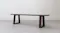 Angled side view of the wooden bench showing its long rectangular seat and two trapezoid-shaped open-frame legs Angled side view of the wooden bench showing its long rectangular seat and two trapezoid-shaped open-frame legs