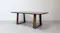 Angled side view of the wooden dining table showing its rectangular top and two trapezoid-shaped pedestal legs Angled side view of the wooden dining table showing its rectangular top and two trapezoid-shaped pedestal legs