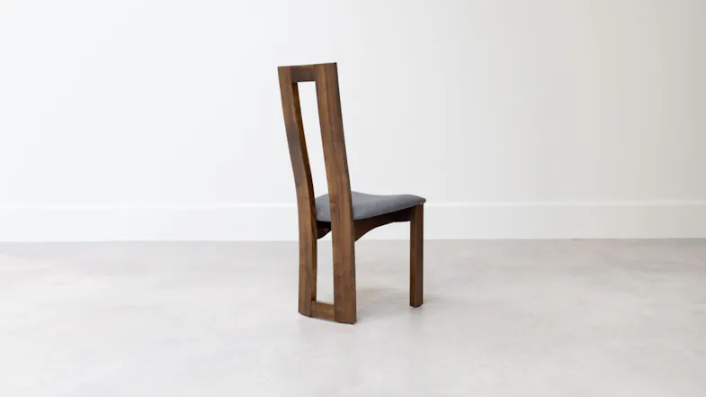 Side view of the wooden dining chair showing the tall open-back design, gently curved backrest, and cushioned seat Side view of the wooden dining chair showing the tall open-back design, gently curved backrest, and cushioned seat