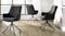 A set of three charcoal upholstered bar stools arranged in a bright room with wood flooring A set of three charcoal upholstered bar stools arranged in a bright room with wood flooring