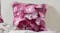 Close-up of a pink floral pillow resting against a neutral wall Close-up of a pink floral pillow resting against a neutral wall