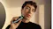 A person using the shaver on his cheek in a warm-lit room A person using the shaver on his cheek in a warm-lit room