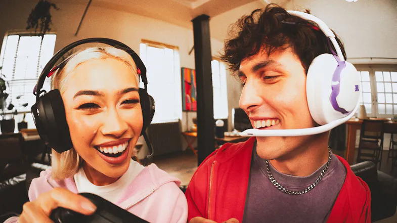 Two people laughing while wearing gaming headsets in a living room Two people laughing while wearing gaming headsets in a living room