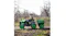 A child is driving a kids’ ride‑on tractor with a trailer loaded with branches in an orchard A child is driving a kids’ ride‑on tractor with a trailer loaded with branches in an orchard