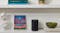 Single black speaker placed on a white bookshelf next to art Single black speaker placed on a white bookshelf next to art