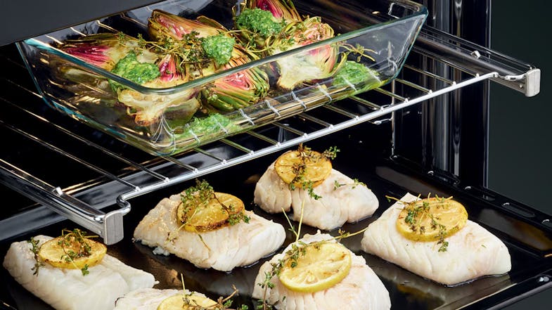 Fish fillets and artichokes are cooking on two levels of the oven Fish fillets and artichokes are cooking on two levels of the oven