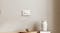 A minimalist interior featuring a white two-button smart light switch mounted on a textured wall above decor A minimalist interior featuring a white two-button smart light switch mounted on a textured wall above decor