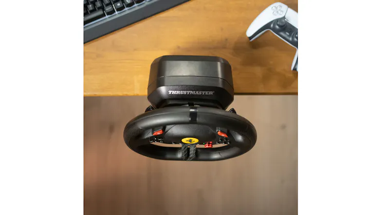 A wheel clamped to the desk with the PS5 controller and keyboard nearby A wheel clamped to the desk with the PS5 controller and keyboard nearby