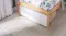 Closed-up view of a white pull-out storage drawer tucked under a bed Closed-up view of a white pull-out storage drawer tucked under a bed