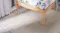 Close-up view of light oak bed legs resting on a ribbed cream rug Close-up view of light oak bed legs resting on a ribbed cream rug