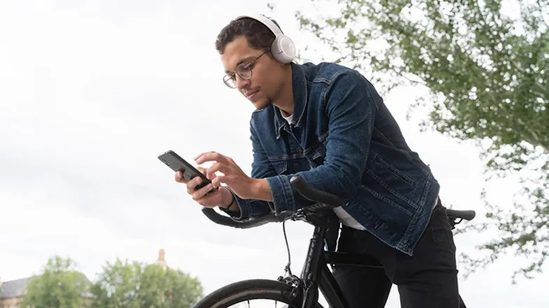 Person on a bicycle wearing JBL headphones outdoors Person on a bicycle wearing JBL headphones outdoors