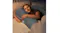 Person lying in bed holding a grey Luxdream J‑shaped pillow in a relaxed position Person lying in bed holding a grey Luxdream J‑shaped pillow in a relaxed position