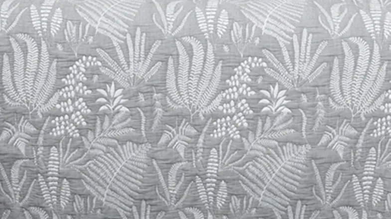 Detailed fabric close‑up showing the silver quilted surface with stitched botanical motifs Detailed fabric close‑up showing the silver quilted surface with stitched botanical motifs