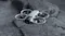 A quadcopter drone hovering over a dark textured rock A quadcopter drone hovering over a dark textured rock