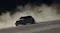 A drone flies behind a grey SUV, kicking up a massive dust cloud A drone flies behind a grey SUV, kicking up a massive dust cloud