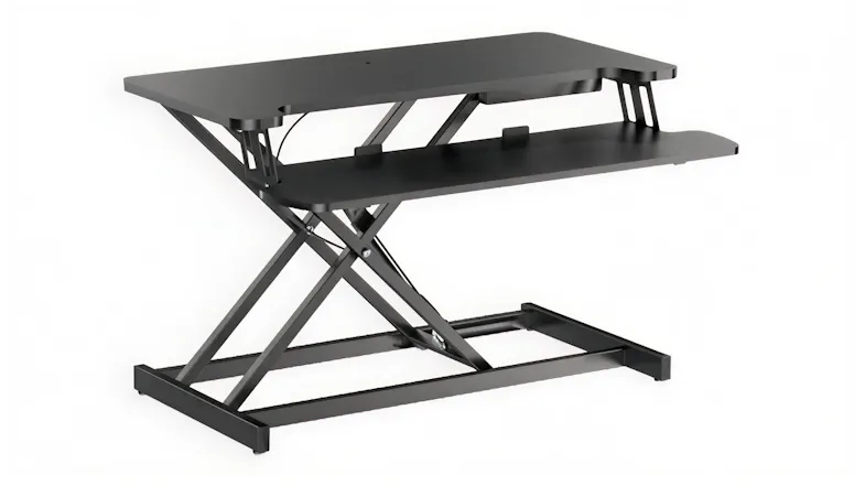Adjustable black Konic Gaslift standing desk converter with an X-shaped lift frame and a two-tier work surface, shown partially raised Adjustable black Konic Gaslift standing desk converter with an X-shaped lift frame and a two-tier work surface, shown partially raised