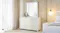 Lumen 6 Drawer Dresser with matching mirror in a white finish, placed beside a bed Lumen 6 Drawer Dresser with matching mirror in a white finish, placed beside a bed