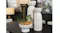 Two tall white textured stoneware vases displayed on a dark table in a decorated room, next to a white fluted bowl planter Two tall white textured stoneware vases displayed on a dark table in a decorated room, next to a white fluted bowl planter