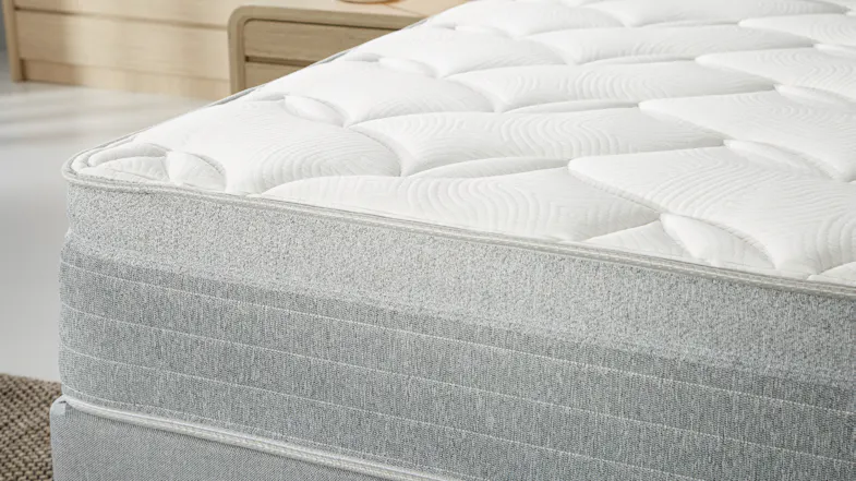 Side close‑up of the mattress edge, focusing on the soft quilted top layer and textured grey fabric Side close‑up of the mattress edge, focusing on the soft quilted top layer and textured grey fabric
