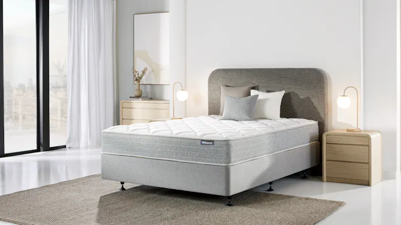 Full view of a Sealy Posture Life Comfort mattress and base set on a rug in a bright room Full view of a Sealy Posture Life Comfort mattress and base set on a rug in a bright room